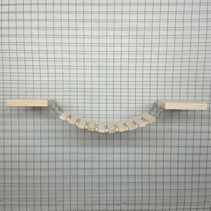 May include: A wooden bridge toy for small animals, featuring a series of connected wooden slats with small wooden balls in between. The bridge is suspended between two wooden platforms.