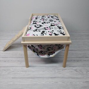 Peut inclure: Un lit pour animal domestique en bois avec une doublure en tissu &agrave; imprim&eacute; panda et une rampe. Le lit a quatre pieds et est fait de bois naturel.