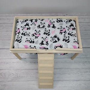 Peut inclure: Un lit pour animal domestique en bois avec une rampe et un rev&ecirc;tement en tissu amovible &agrave; imprim&eacute; panda. Le rev&ecirc;tement est blanc avec des pandas noirs et blancs tenant des ballons roses.