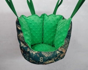 May include: A green and gold fabric hanging bed for small pets, with a soft green lining and a floral pattern.