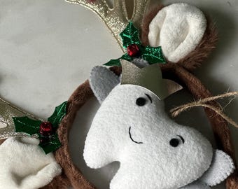 May include: A brown headband with a white tooth with a crown and a pair of reindeer antlers with red berries and green holly leaves.