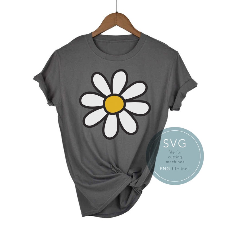 Puede incluir: Una camiseta gris con un gr&aacute;fico de margarita blanca. La margarita tiene un centro amarillo. El texto "SVG file for cutting machines PNG file incl." est&aacute; en un c&iacute;rculo en la parte inferior derecha de la imagen.