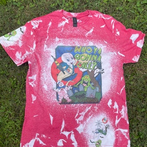 May include: Red t-shirt with a white bleach design featuring the Ghostbusters logo and characters. The text on the shirt reads "Who Ya Gonna Call?"