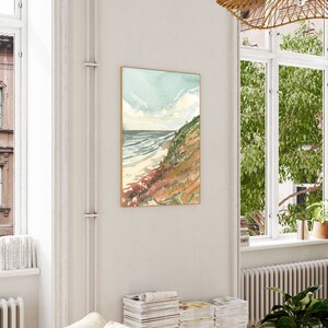 May include: A vertical rectangular wall art print featuring a watercolor landscape of a coastal cliffside meeting the ocean. The scene displays a sandy beach, rolling waves, and a grassy hillside in shades of green, brown, and soft blue sky.