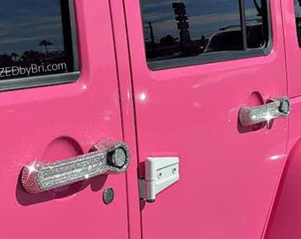 May include: A bright pink Jeep Wrangler with a white stripe along the roof. The vehicle has diamond-encrusted door handles and a black tyre with a white rim.