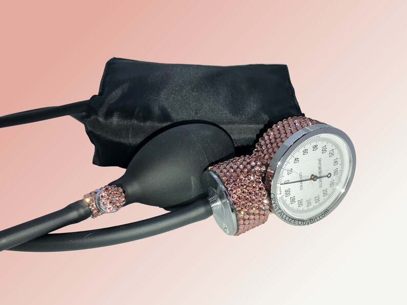 May include: A black blood pressure cuff with a silver gauge and a pink rhinestone-covered pump. The gauge reads "CRYSTALLIZED BY BTI.COM".