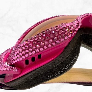 K&ouml;nnte beinhalten: Hei&szlig;rosa Brille mit rosa Strasssteinen besetzt. Die Brille hat ein schwarzes Schaumstofffutter und eine hellbraune Linse. Der Text "CrystallizedByBri.com" ist sichtbar. Ein gestreiftes Stoffband ist befestigt.