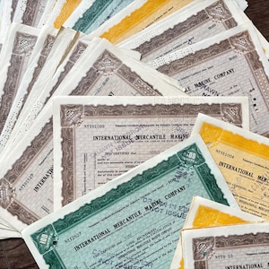 May include: A collection of vintage stock certificates in various colors, including green, yellow, and brown. The certificates feature ornate borders, text, and the name "International Mercantile Marine Company."