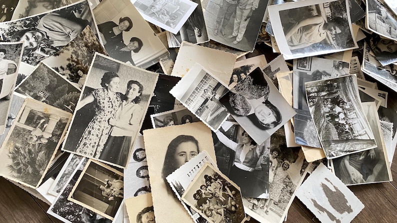 May include: A pile of black and white photographs, some with people in them, others with landscapes or buildings. The photos are arranged in a random order, and some are overlapping.