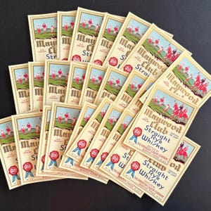 May include: A collection of rectangular paper labels for Maywood Club Straight Rye Whiskey. Each label features a vintage illustration of people playing polo on horseback, with cream-colored backgrounds, blue borders, and red seal graphics.