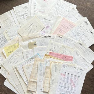 May include: A scattered assortment of vintage documents, including financial records and receipts. The papers are of various sizes and colours, some with handwritten notes and stamps. The documents are from Bache and other companies.