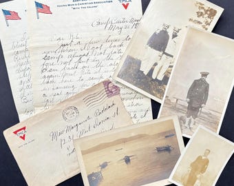 May include: A collection of vintage photographs, letters, and an envelope. The letters are from the Army and Navy YMCA, with the text "WITH THE COLORS." The photographs depict men in military uniforms and a scenic lake view.