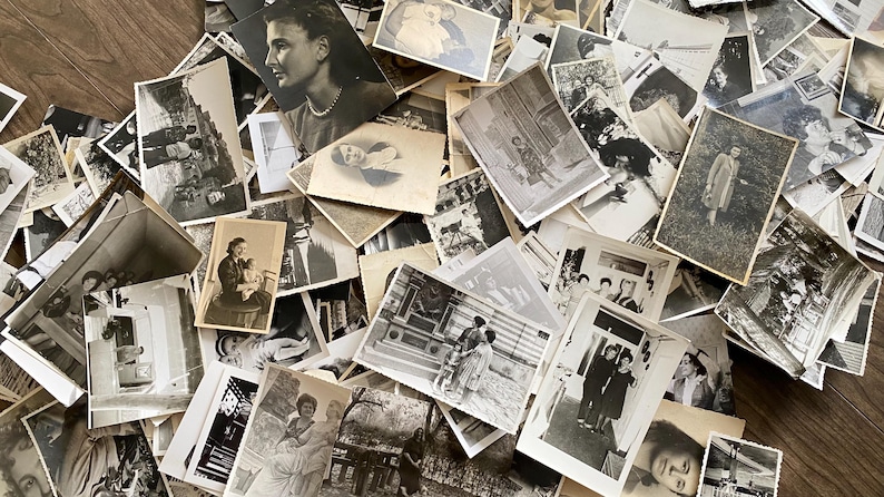May include: A large pile of black and white photographs, some with people, some with landscapes, and some with objects. The photographs are arranged in a random order and are all different sizes.