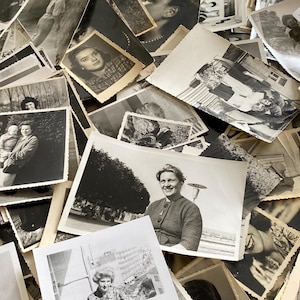 May include: A large pile of black and white photographs, some with people, some with landscapes, and some with buildings. The photos are all different sizes and shapes, and they are arranged in a random order.