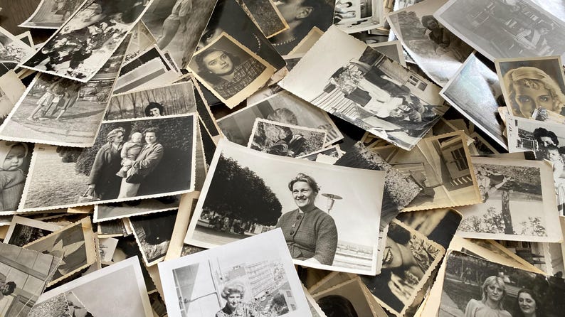 May include: A large pile of black and white photographs, some with people, some with landscapes, and some with buildings. The photos are all different sizes and shapes, and they are arranged in a random order.