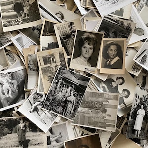 May include: A large pile of black and white photographs, many of which feature people. The photos are arranged in a random order, and some are overlapping.