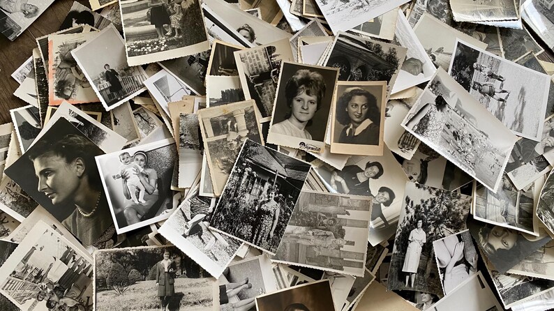 May include: A large pile of black and white photographs, many of which feature people. The photos are arranged in a random order, and some are overlapping.