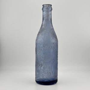 Peut inclure: Une bouteille en verre bleu vintage avec du texte en relief. La bouteille a un long col et une base arrondie. Le texte sur la bouteille indique "Soda Water" et "Toronto". Il s'agit probablement d'une ancienne bouteille de soda.
