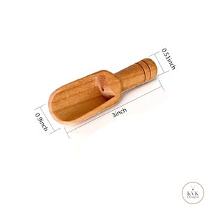 May include: A small, light brown wooden scoop with a handle. The scoop is 3 inches long, 0.9 inches wide, and 0.51 inches deep. The handle has three carved grooves. The scoop is designed for measuring dry ingredients.