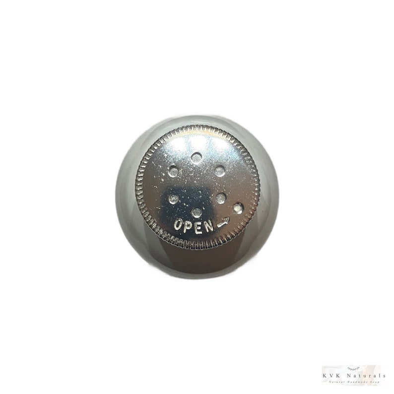May include: A silver metal shaker top with a circular design. The top has several small holes and the word "OPEN" is printed on the surface. The shaker top is designed to dispense contents.
