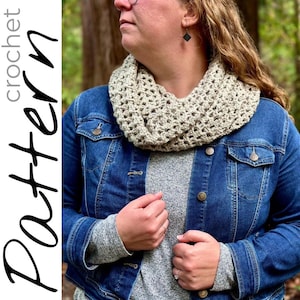 May include: A beige crochet infinity scarf with a textured stitch pattern. The scarf is worn by a person wearing a denim jacket and a gray shirt.