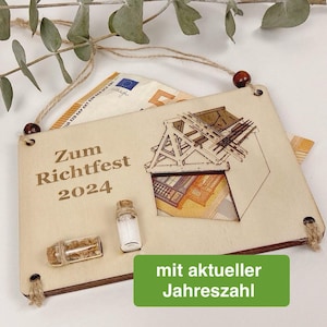 Könnte beinhalten: Holz Schild mit dem Text "Zum Richtfest 2024" und einer kleinen Haus Illustration. Das Schild hat zwei kleine Glasfläschchen mit Korken. Das Schild ist mit einer Juteschnur und Holzperlen verziert.