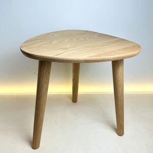 May include: A light wood triangular side table with three legs.