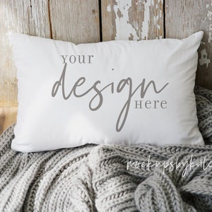 May include: White pillow with the text "Your design here" on a gray knitted blanket.