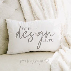 May include: White throw pillow with the text "Your design here" on a white sofa with a white blanket.