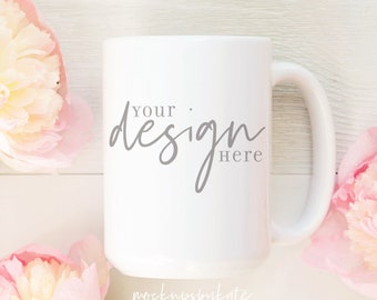 Könnte beinhalten: Eine weiße Keramik-Kaffeetasse mit Henkel. Auf der Tasse steht in grauer Schrift "Your design here". Die Tasse ist von rosa Pfingstrosen umgeben.
