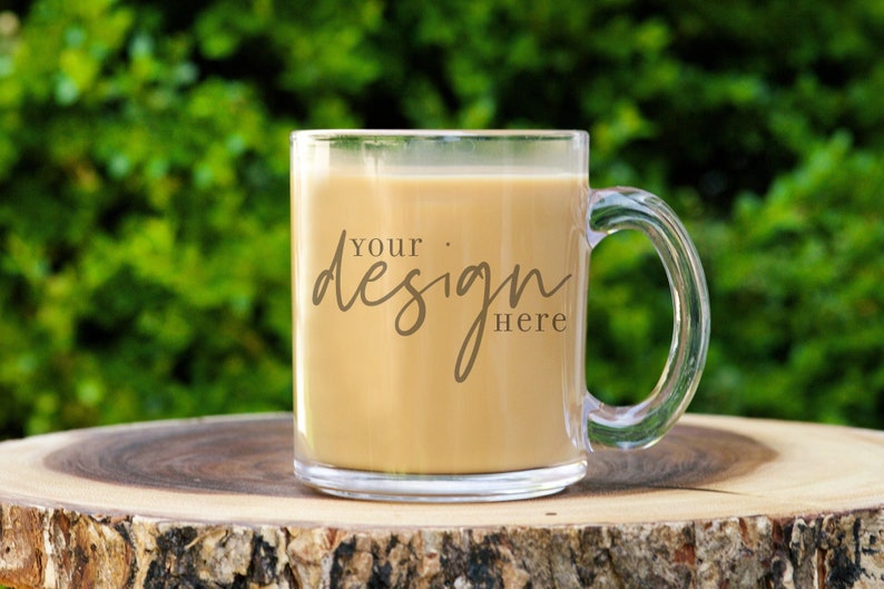 May include: A clear glass mug with a handle filled with coffee. The mug has the text "Your design here" printed on the side.