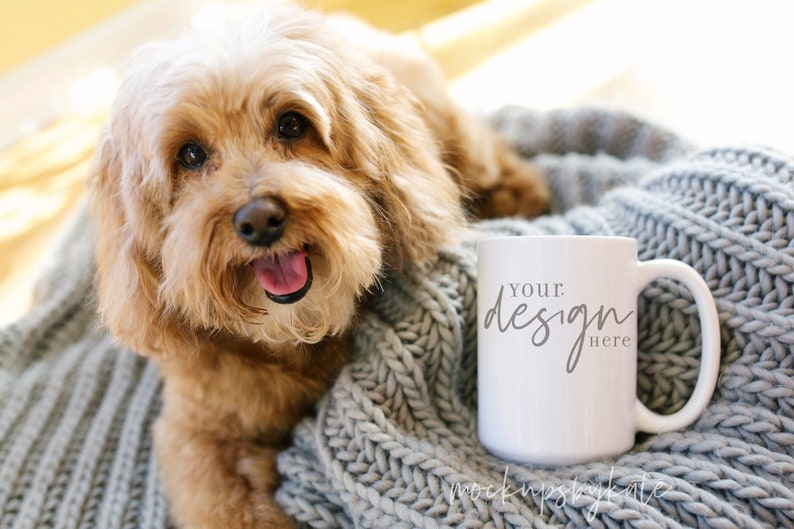 K&ouml;nnte beinhalten: Eine wei&szlig;e Keramiktasse mit einer grauen Strickdecke und einem braunen Hund. Die Tasse tr&auml;gt den Text "Your Design Here".