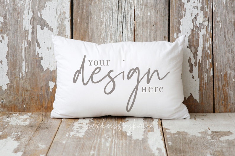 Puede incluir: Almohada blanca con una inscripci&oacute;n gris que dice "Your design here" sobre un fondo de madera r&uacute;stica.