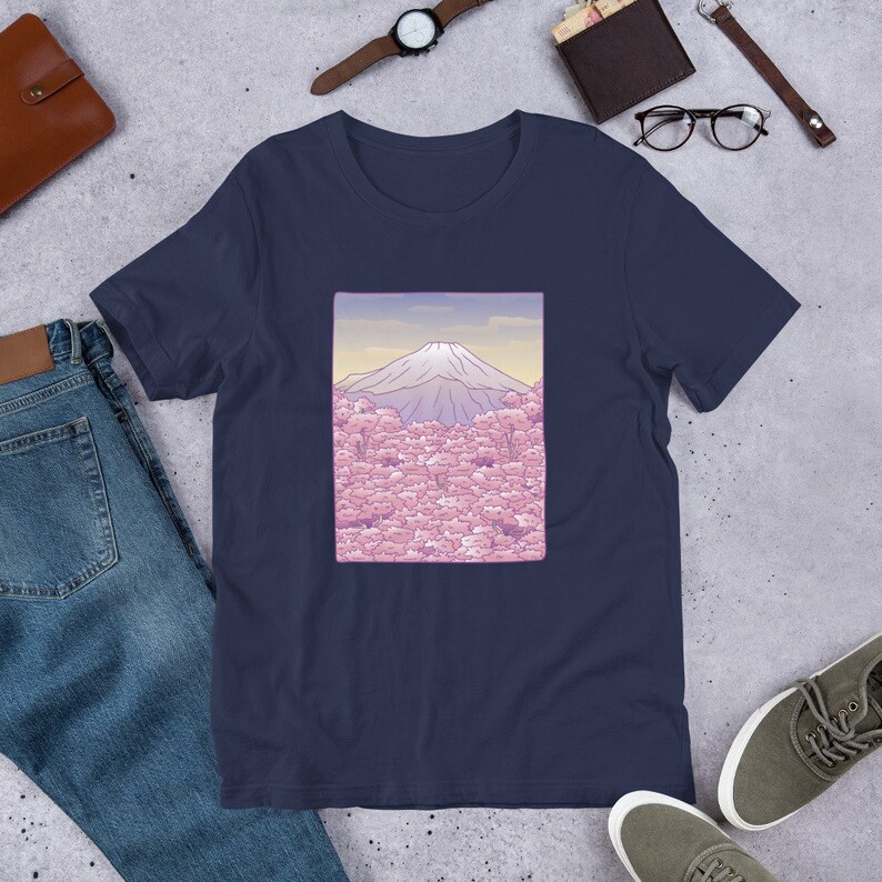 Puede incluir: Una camiseta azul marino con un gr&aacute;fico de Mount Fuji y flores de cerezo rosas. El gr&aacute;fico est&aacute; enmarcado en un rect&aacute;ngulo morado claro.