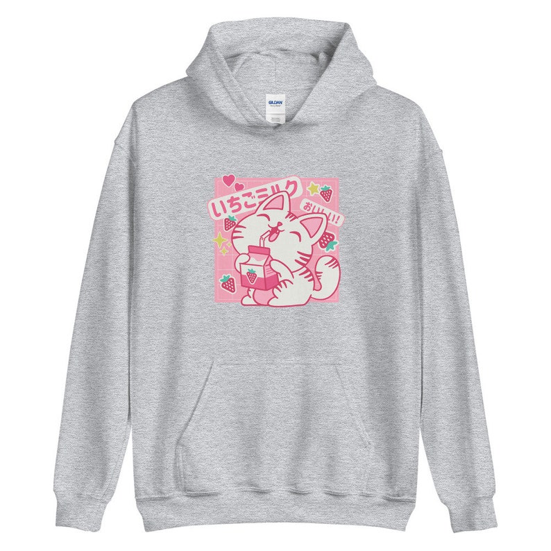 K&ouml;nnte beinhalten: Hellgrauer Kapuzenpullover mit einem rosa quadratischen Aufdruck, der eine Comic-Katze beim Trinken von Erdbeermilch zeigt. Der Aufdruck enth&auml;lt japanischen Text, Erdbeeren und Sterne. Der Kapuzenpullover hat eine Kapuze und eine Vordertasche.