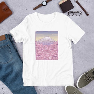 Puede incluir: Camiseta blanca con un gr&aacute;fico de Mount Fuji y flores de cerezo rosas.
