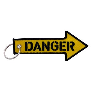 Puede incluir: Llavero en forma de flecha amarillo y negro con la palabra "DANGER" impresa en negro.