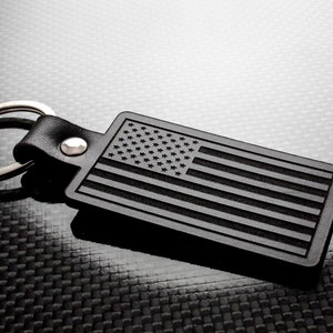 May include: Black leather keychain with a silver ring and a black rubber tag featuring an embossed American flag design.