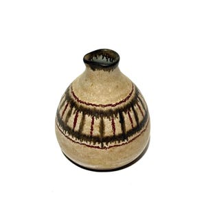 May include: A small, round ceramic vase with a narrow neck. The vase has a beige base color with a dark brown and red striped pattern around the middle. The rim of the vase is dark brown.