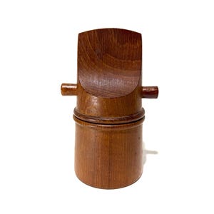 May include: A wooden container with a lid and two small handles. The container is cylindrical with a curved top and a dark brown finish. The lid is a darker shade of brown.
