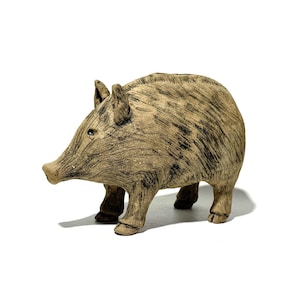 May include: A ceramic figurine of a wild boar, featuring a textured, brown and black finish. The boar is depicted in a standing position with its snout forward, ears perked, and four legs firmly planted. The figurine is set against a white background.