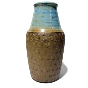 May include: A handcrafted ceramic vase with a light blue top and a brown, textured body. The vase features a repeating oval pattern on the lower portion. The vase is a decorative item for the home.