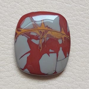 Pu&ograve; includere: Un cabochon di diaspro rosso, grigio e giallo con un motivo astratto unico. Il cabochon &egrave; liscio e lucido, con una finitura lucida.