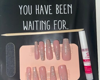 Peut inclure: Un ensemble de faux ongles press-on rose et argent pailletés avec une lime à ongles, un pousse-cuticules en bois et un flacon de colle à ongles. L'emballage comprend le texte "I AM WHAT YOU HAVE BEEN WAITING FOR."