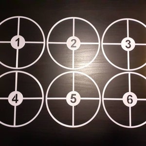 Könnte beinhalten: Sechs weiße Kreise mit schwarzen Umrissen und den Zahlen 1 bis 6 in der Mitte. Die Kreise sind in zwei Reihen zu je drei angeordnet.