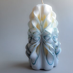 May include: A white and blue carved candle with a decorative design. The candle is shaped like a flower with intricate details.