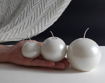 Pearl set of three round carved candles of different sizes.