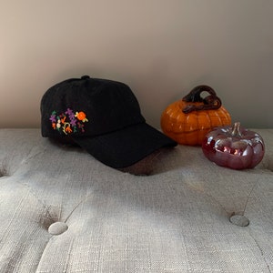 black cap with orange and purple flowers, black hat with hand embroidery of orange flowers and red berries, purple flowers on hat