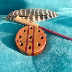 May include: A wooden fletching jig with red and brown stripes and nine holes. The jig is labeled "H.C. CLUEKS".