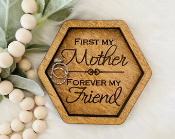 May include: Wooden ring dish with the text "First my Mother Forever my Friend" engraved on it. The dish is hexagonal in shape and has a dark brown stain.